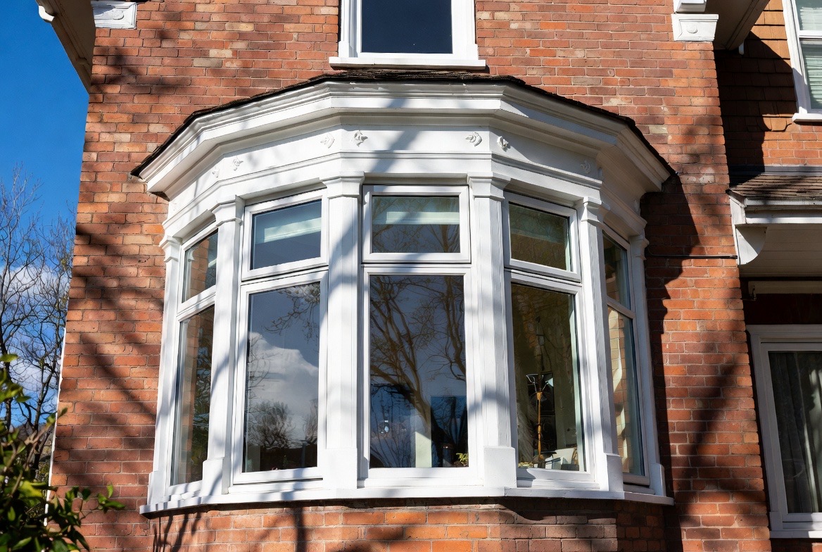 Curved bow window with an ornate white surround on a brick exterior