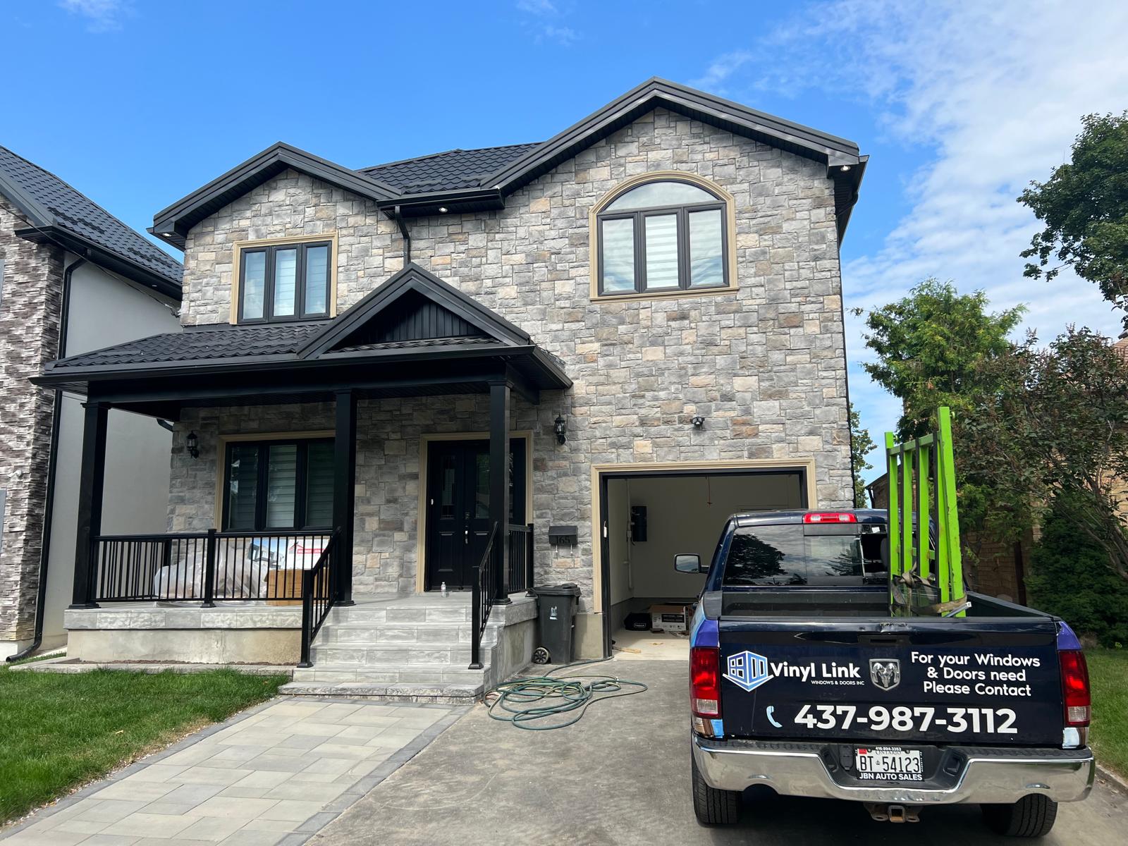 Vinyl Link work truck parked in front of a completed new-build home with all new windows and entry door