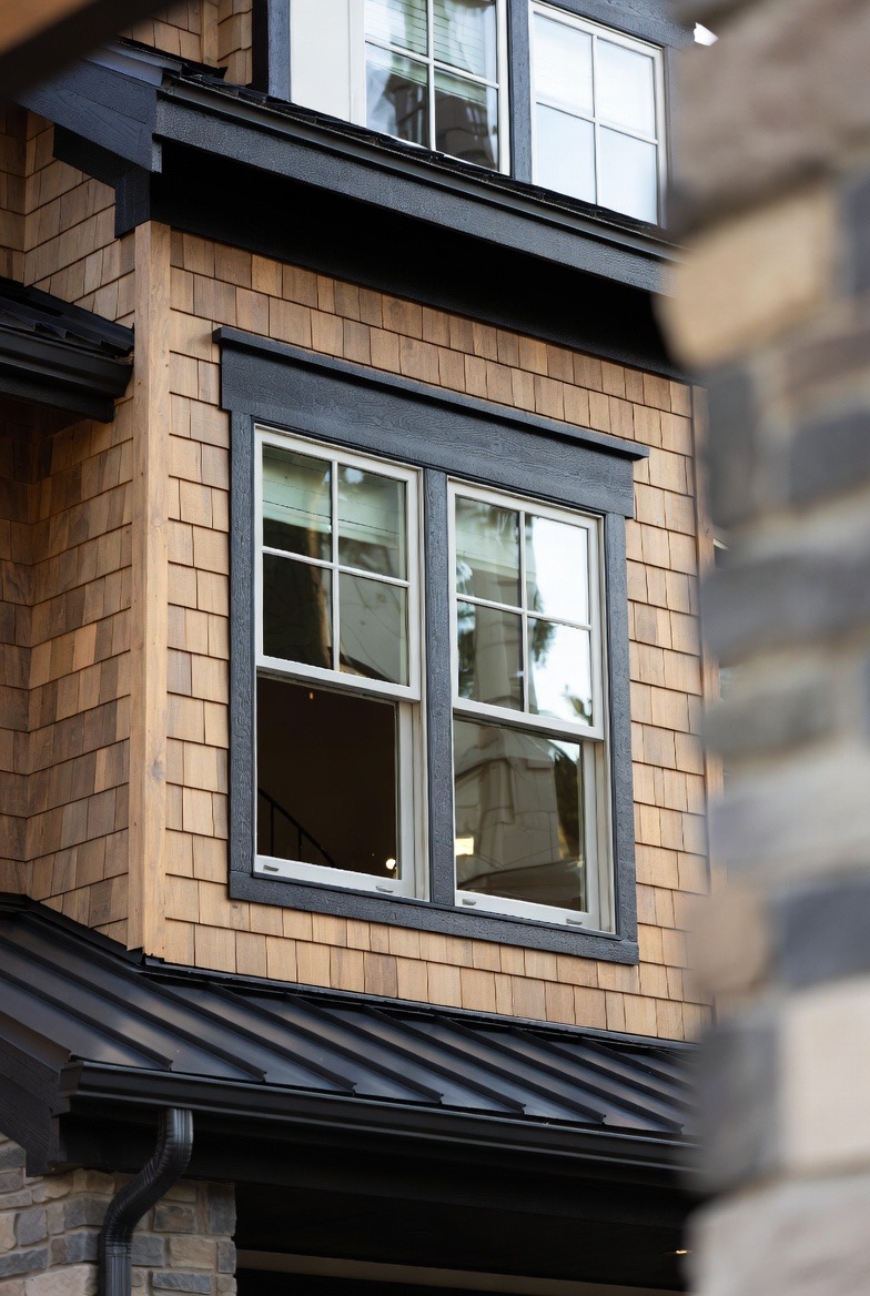 Double-hung window with grille pattern on a cedar-shingled exterior