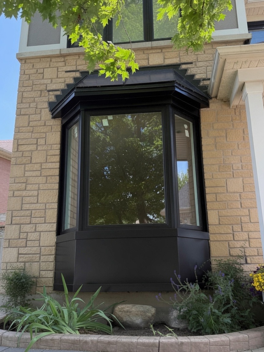 Modern black-framed bow window installed on a stone home exterior