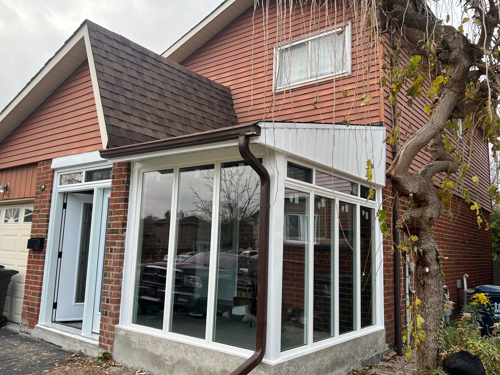 Three-season sunroom addition with full glass walls and white vinyl trim